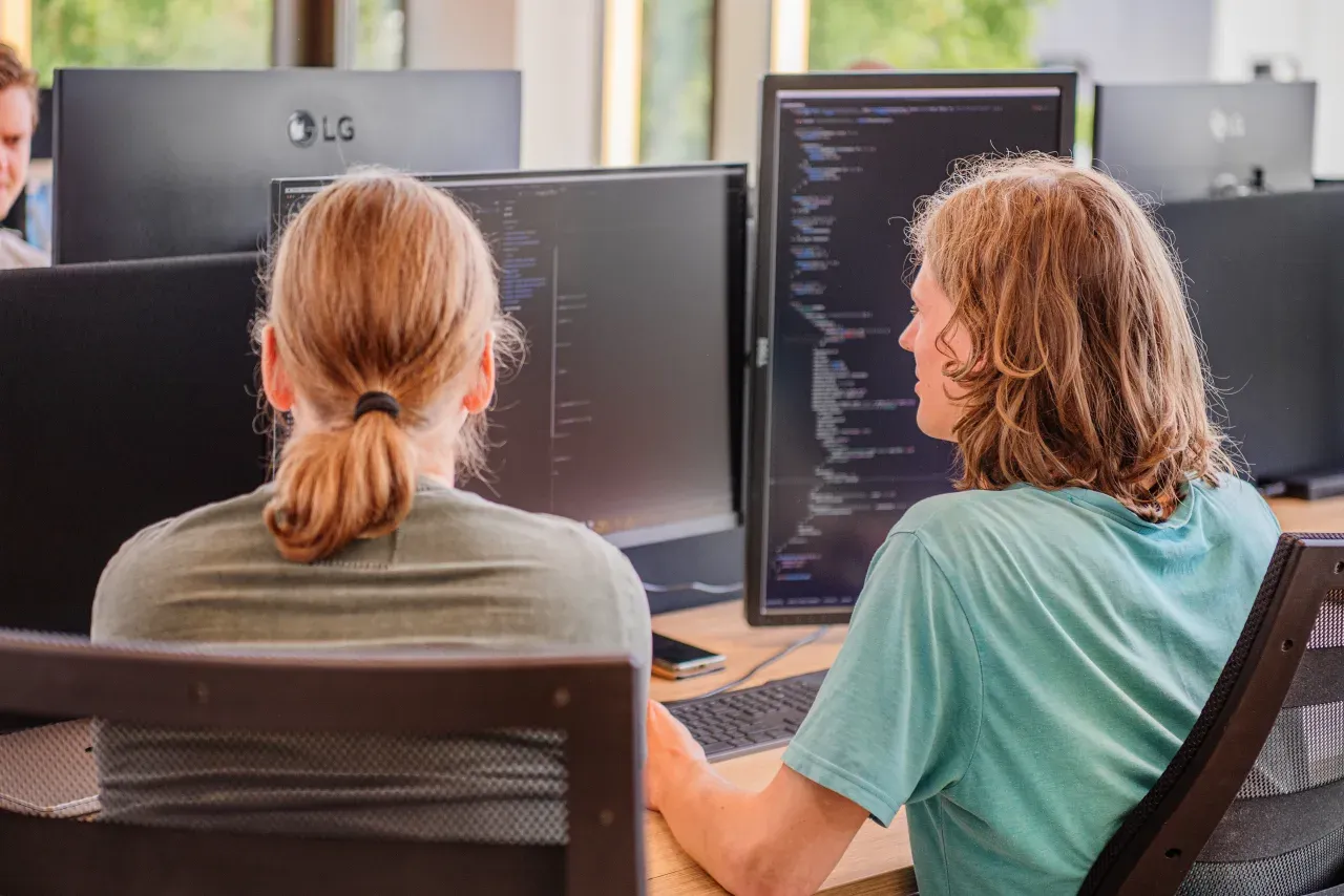 Twee ontwikkelaars van Meierij IT kijken samen naar code op het scherm