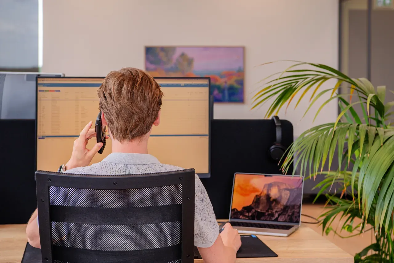 Medewerker van Meierij IT werkt aan de telefoon in een webapplicatie op twee schermen